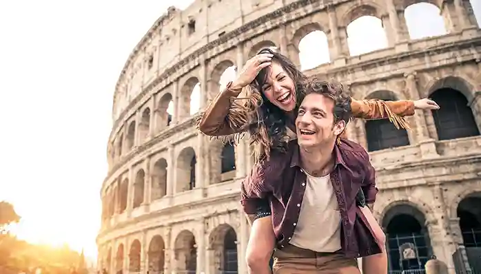 A woman piggybacking on a man in front of the Colosseum in Rome, Italy